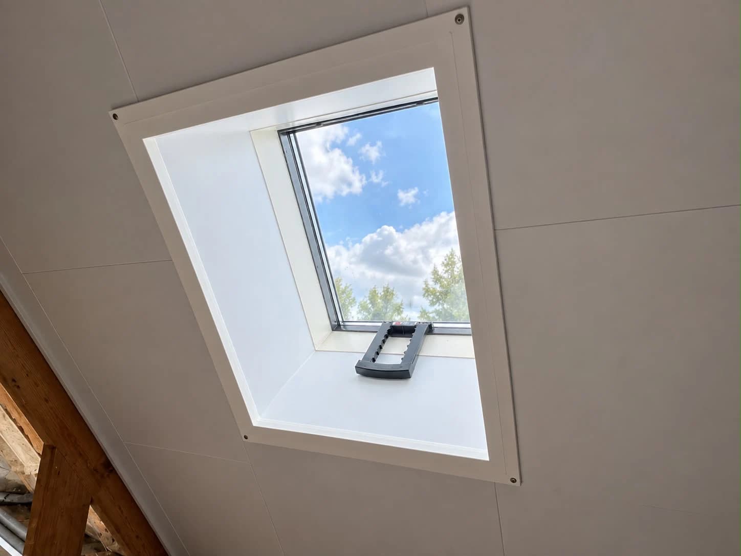 Roof window with white interior finishing in a renovated attic in Assen