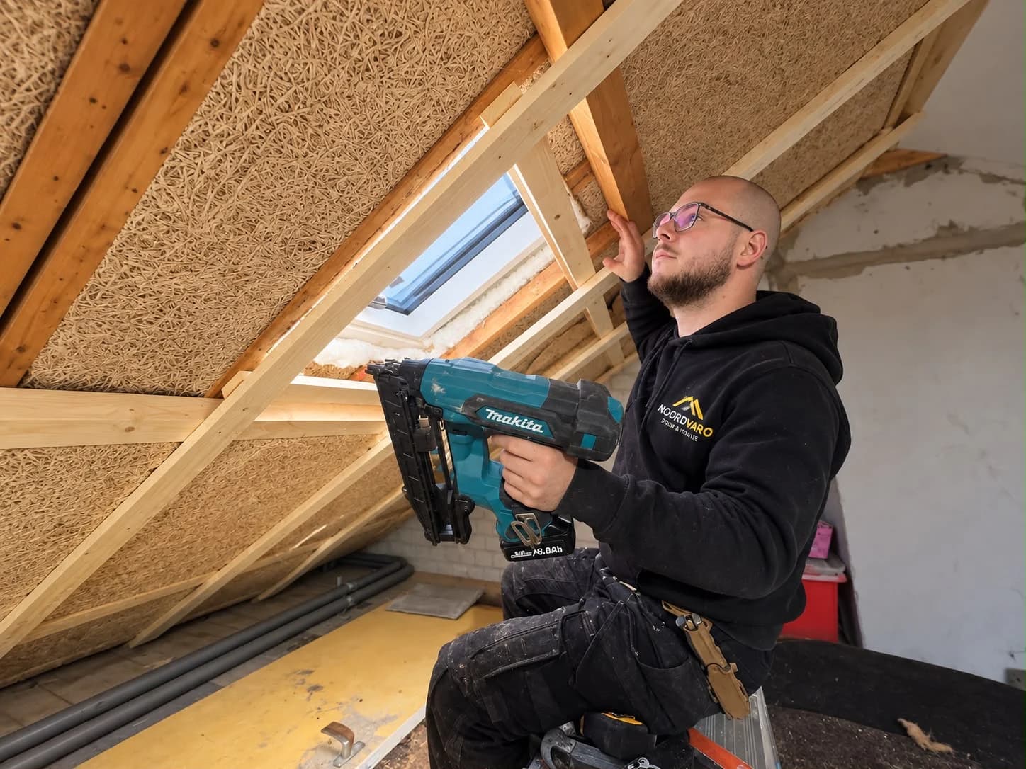 A Noordvaro specialist installs timber battens beside a roof window in a home in Assen