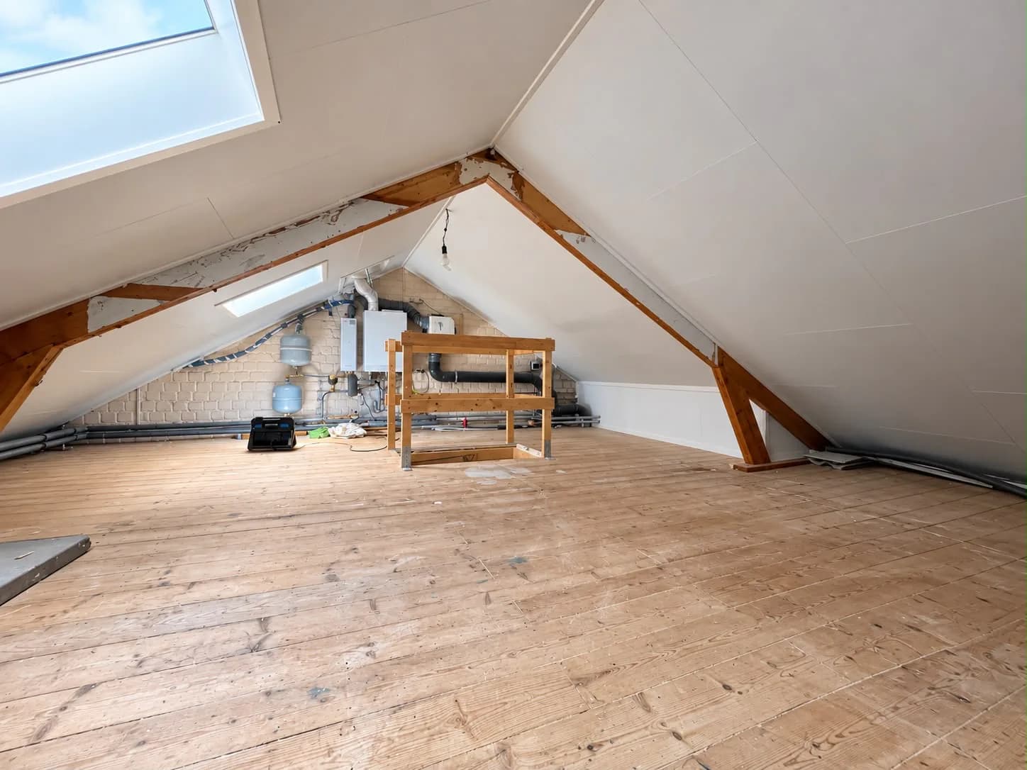 Wide view of the attic in Assen after insulation and white panel finishing, with two roof windows