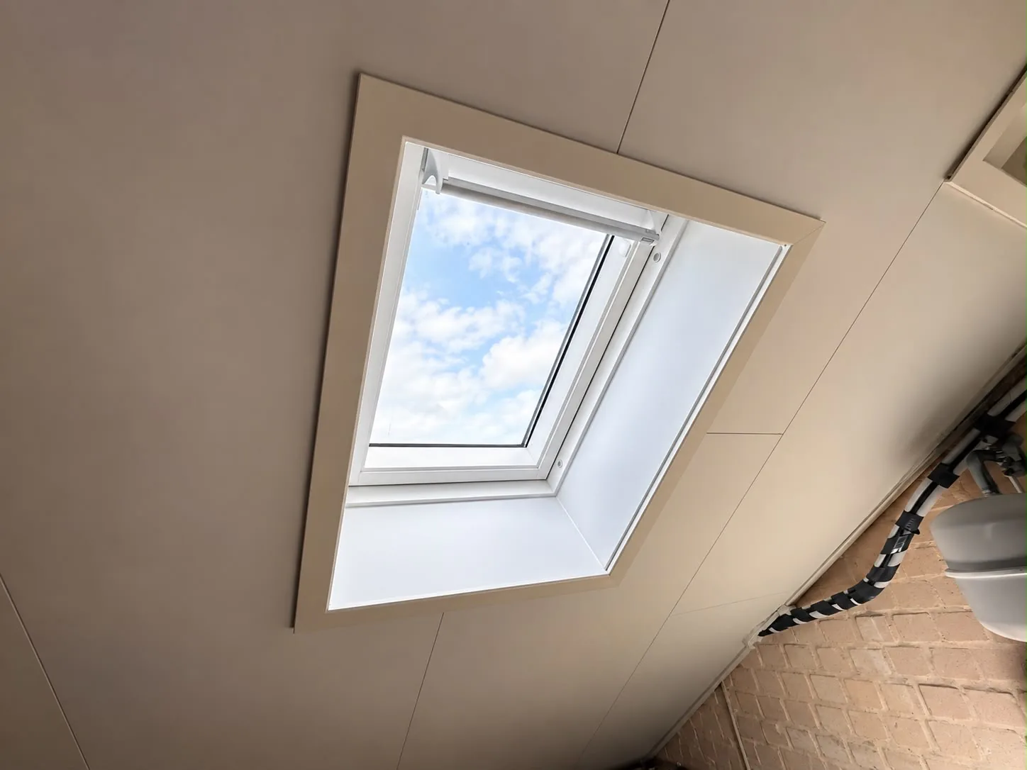 Nieuw wit VELUX-dakraam met afgewerkte binnenaansluiting in het schuine dak