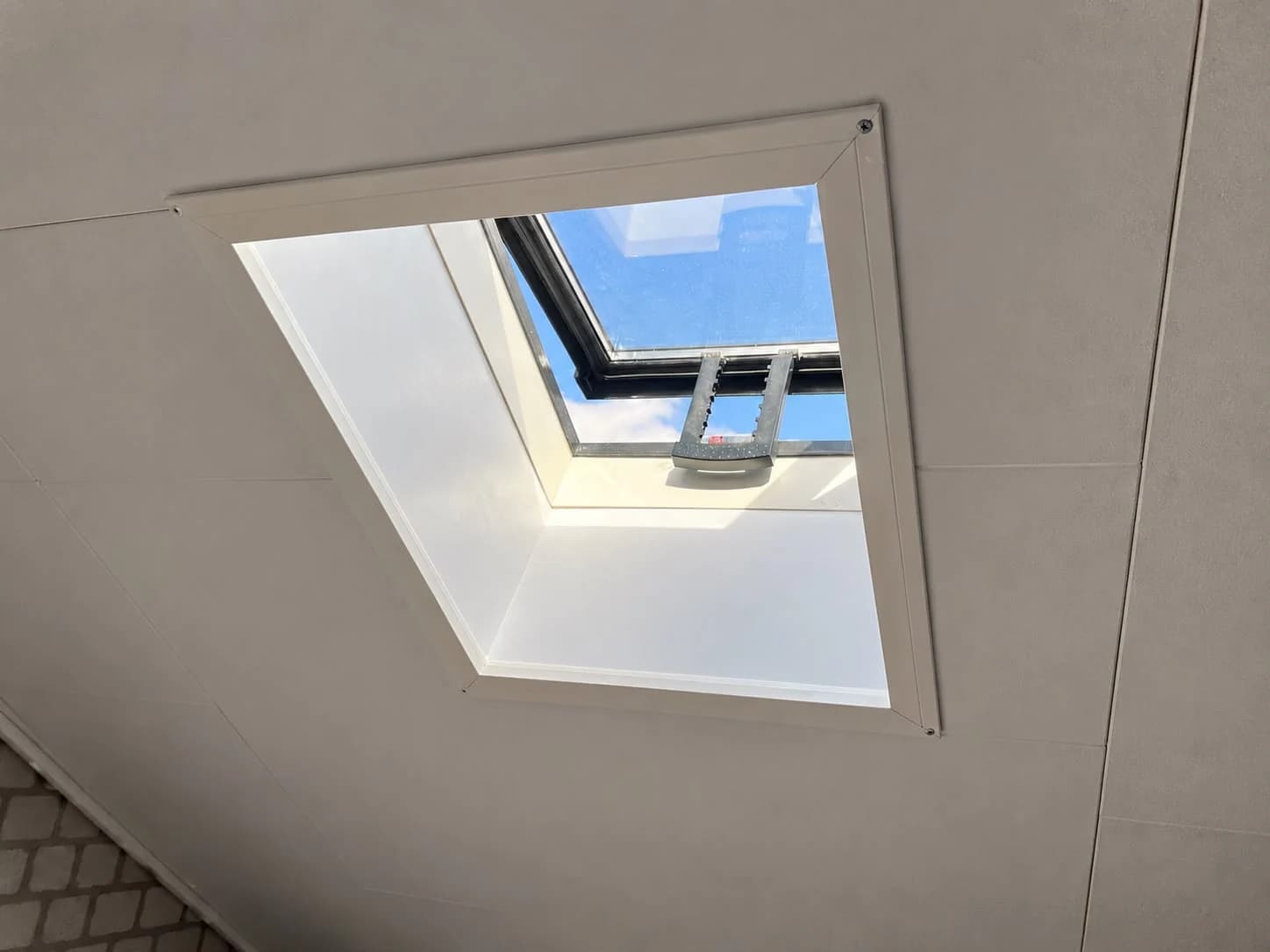 Sunlight enters through a roof window with white interior lining and a visible operating handle