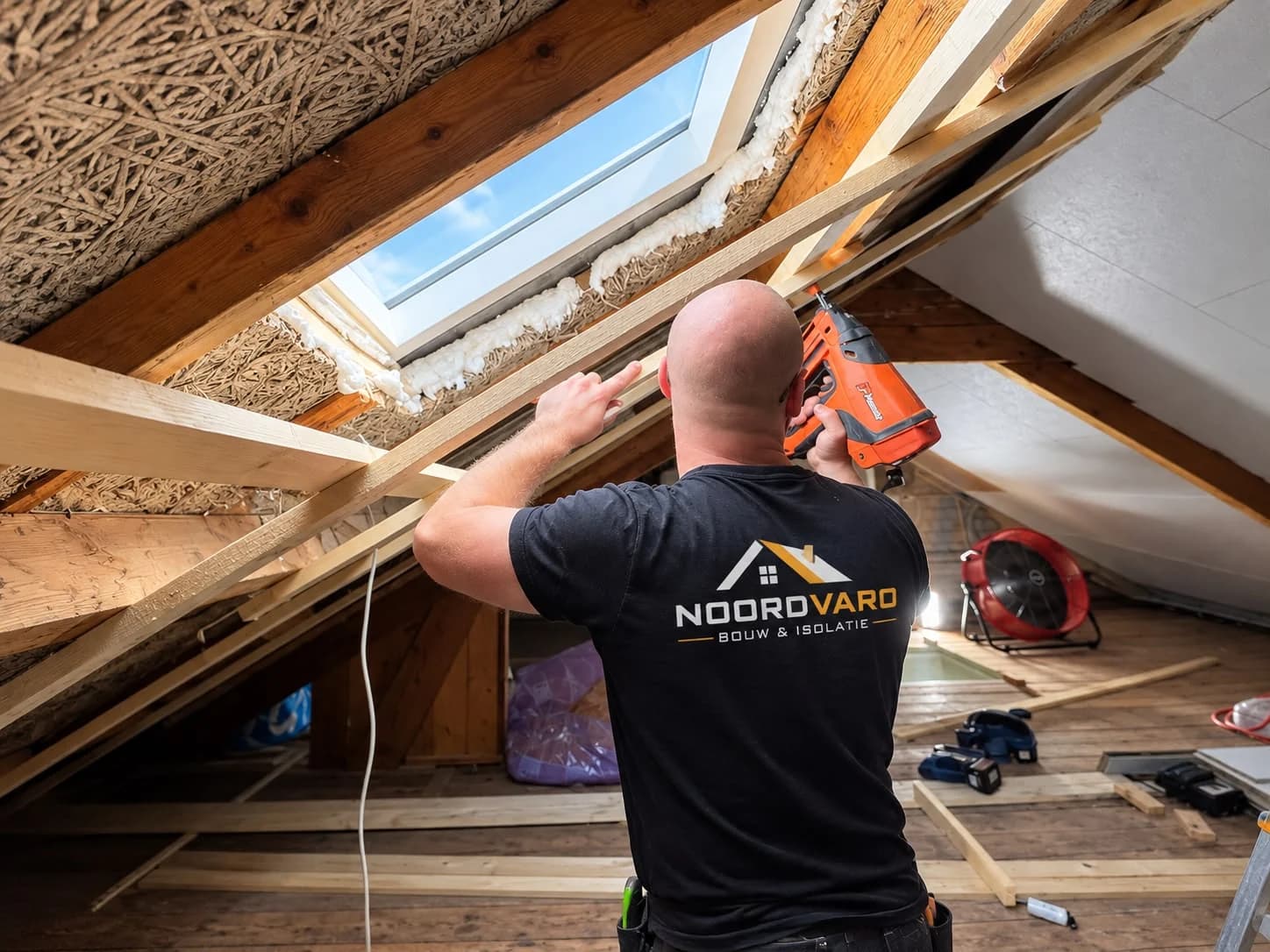 Worker in Noordvaro clothing working on timber battens beside a roof window