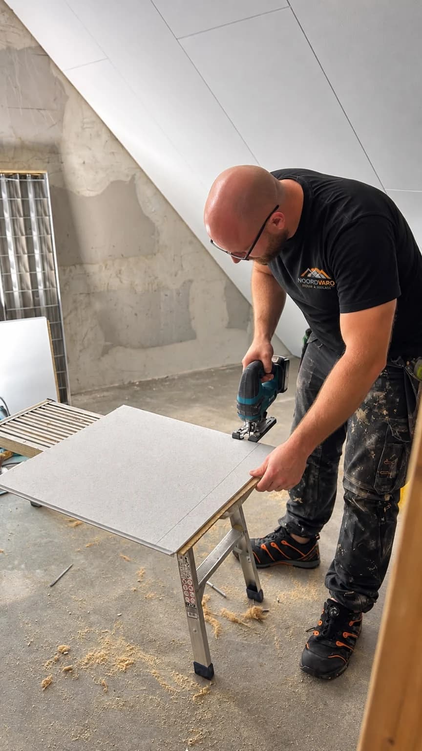 Worker in Noordvaro clothing cutting a finishing panel on a work support in an attic