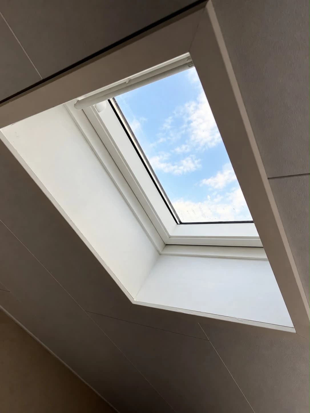 Detail of white interior lining around a VELUX roof window with a top control bar