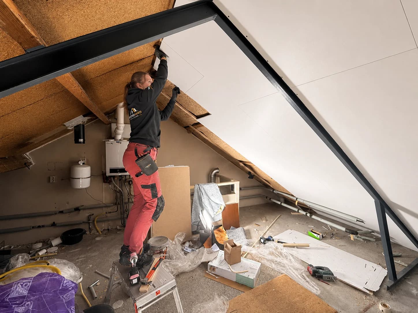 A Noordvaro team member installs Agnes finishing panels below a pitched roof