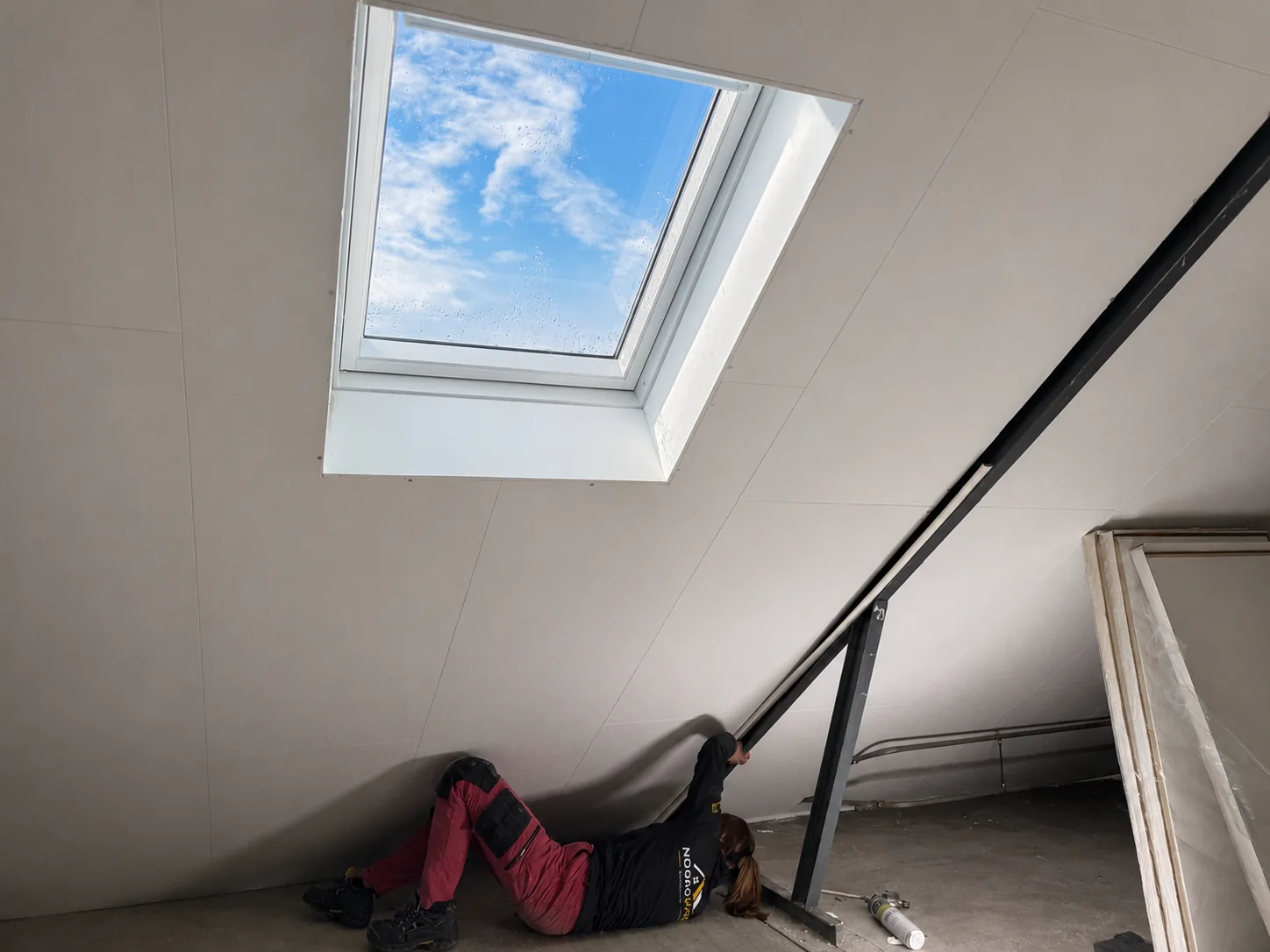 A Noordvaro team member works below a roof window on the interior ceiling finish