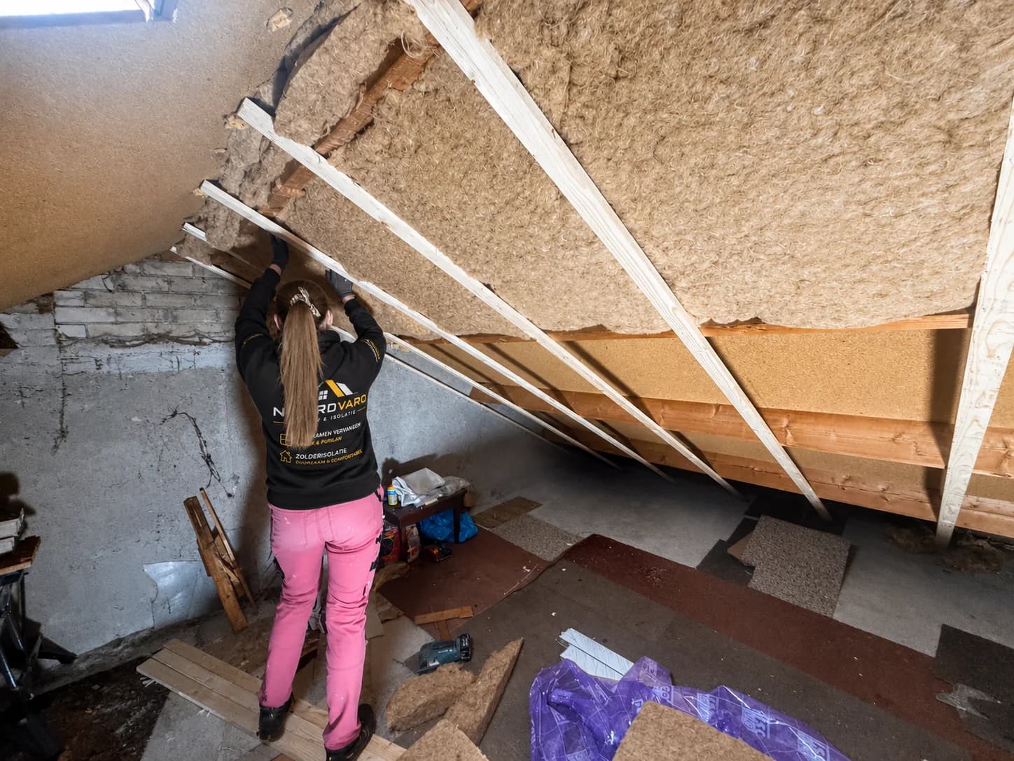 A Noordvaro team member fits insulation inside a pitched roof