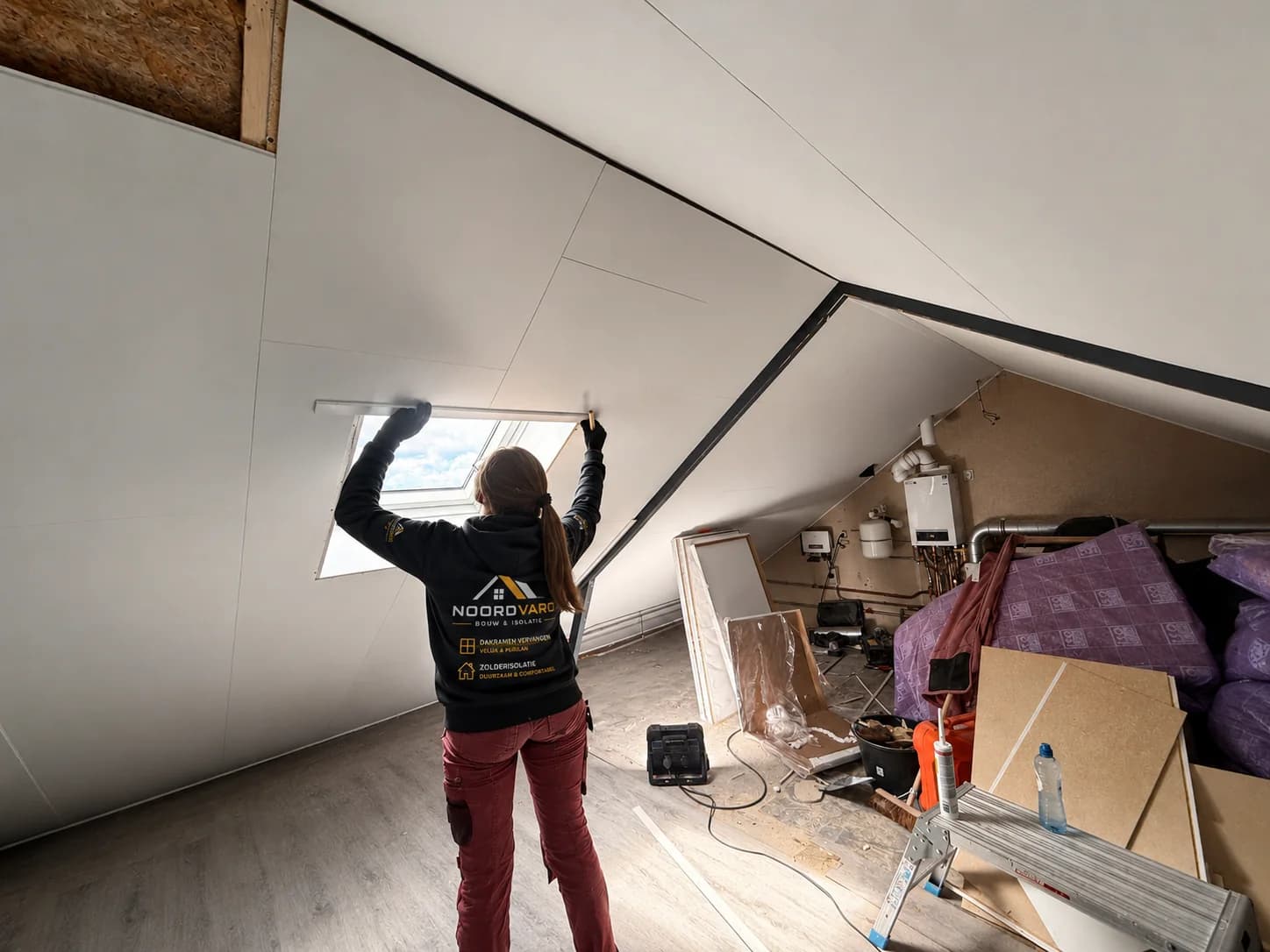 Noordvaro teamlid werkt aan de binnenafwerking rond een dakraam in een zolderruimte